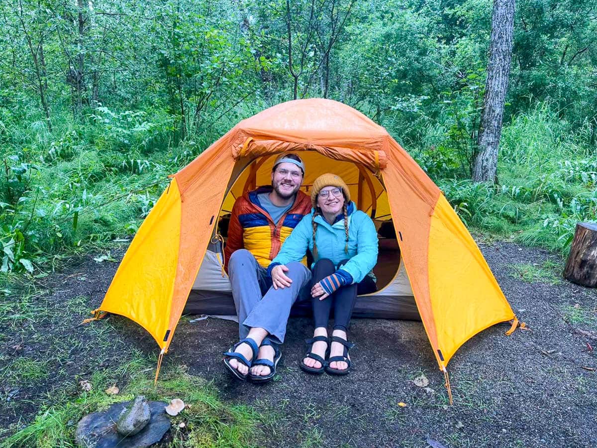 Couple sitting in a tent in a rainforest in Katmai National Park in Alaska