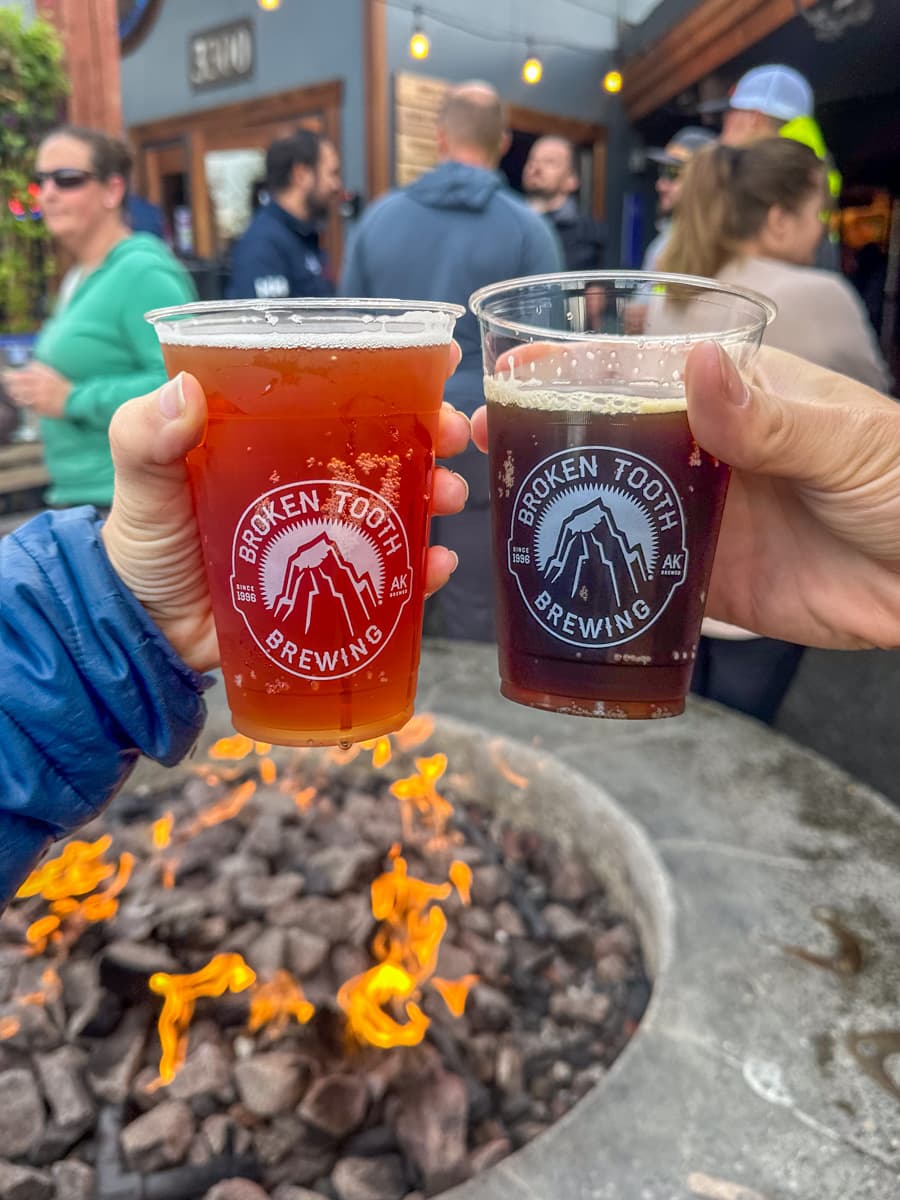 Couple holding beer from the Moose's Tooth Pub and Pizzeria over a firepite in Anchorage, Alaska