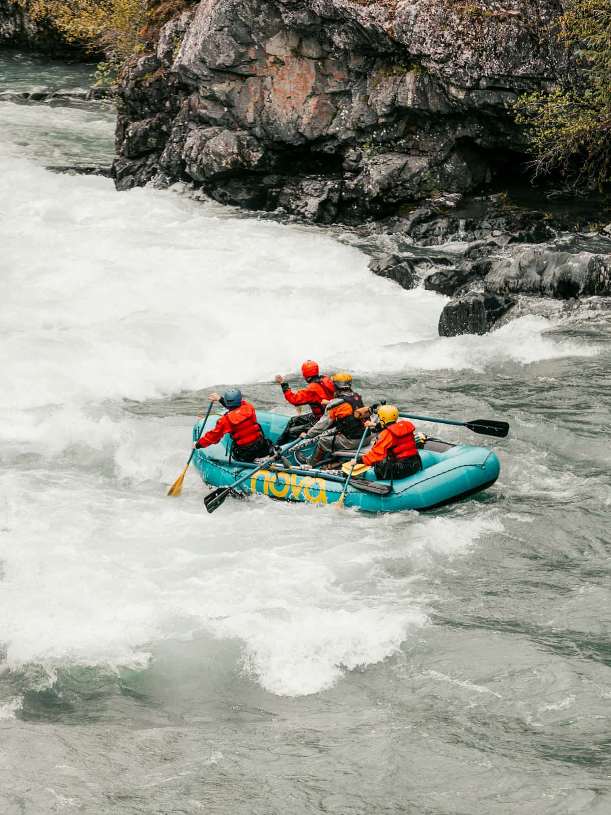 Group rafting down the Nenana River with rocky canyons in the background in Alaska