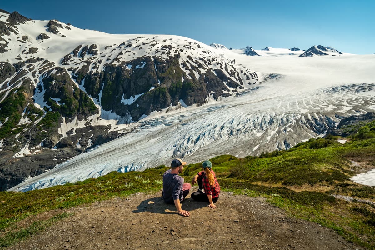 Couple sitting and overlooking the Harding Icefield with mountains in the backgroudn in Kenai Fjords National Park in Seward, Alaska