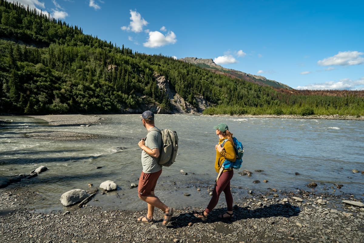 Couple walking along the rocky shoreline of the Nenana River along the Horseshoe Lake Trail in Denali National Park in Alaska