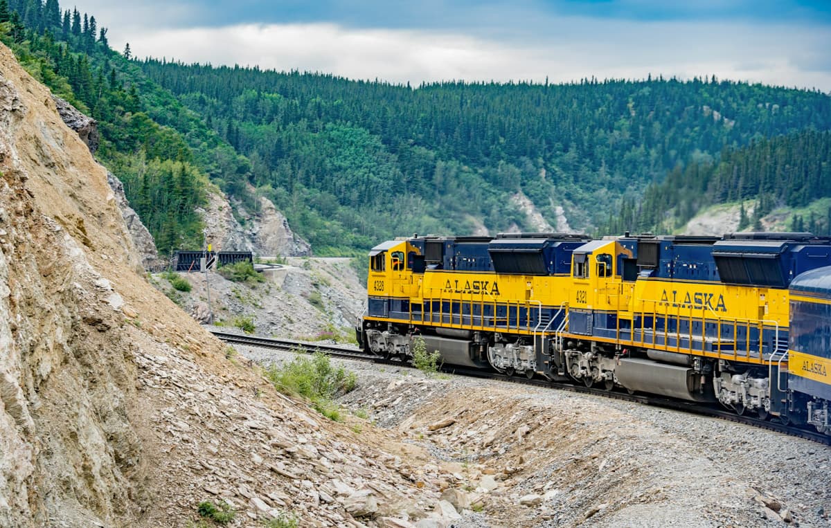 Alaska Railways leading along a rocky canyon with pine trees in the background in Alaska