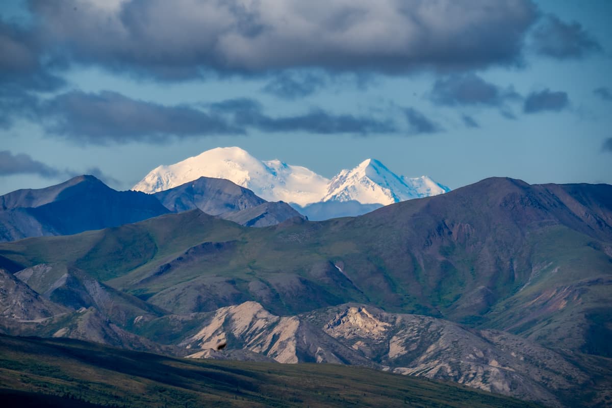 Snowy peak of Mount Denali with the layers of the Alaska Mountain range in the foreground along the Mount Healy Overlook Trail in Denali National Park in Alaska