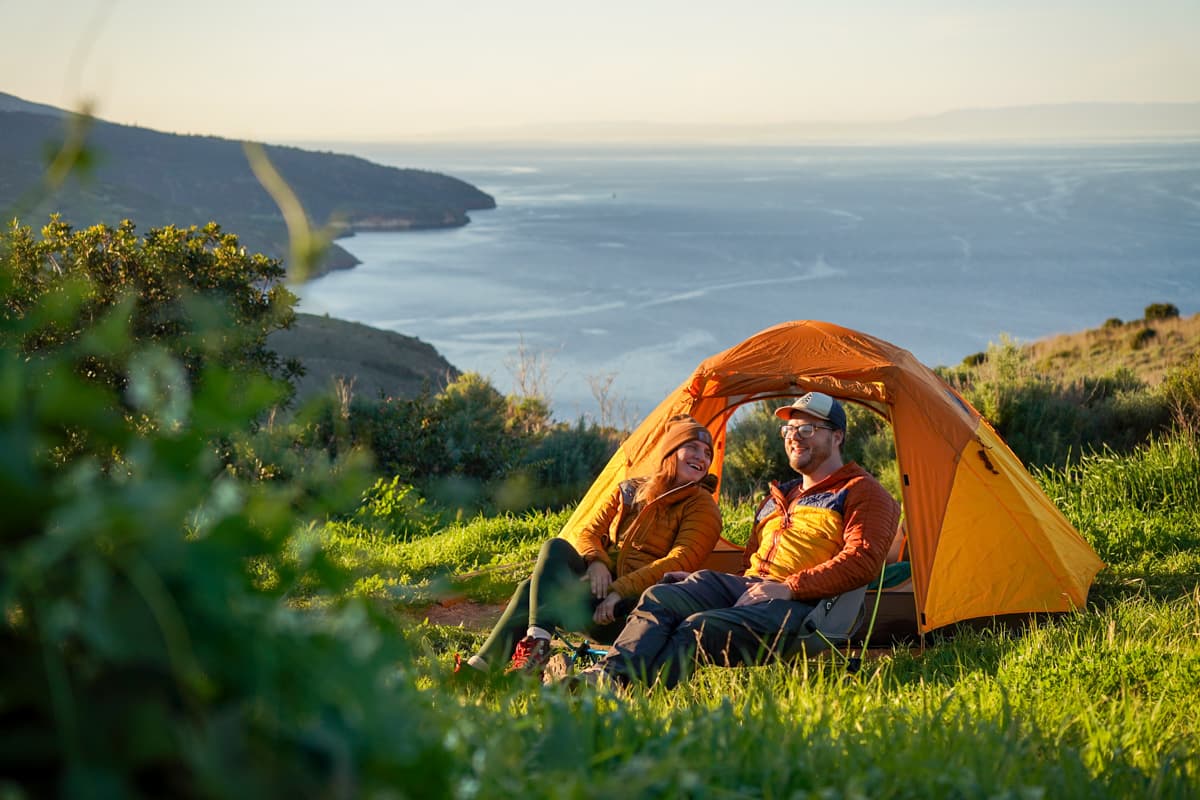 Couple sitting in front of a tent at the Del Norte Campground at Santa Cruz island in the Channel Islands