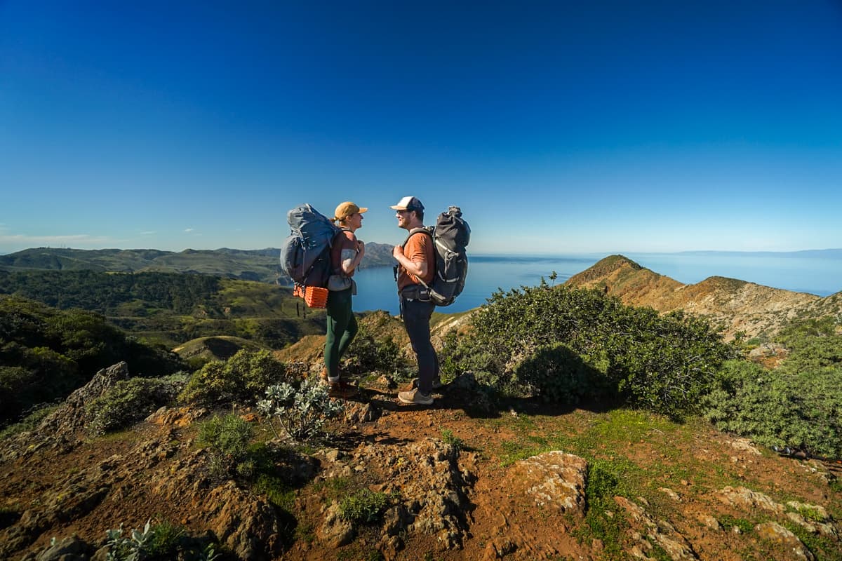 Couple standing with backpacks near High Mount on Santa Cruz Island on Channel Islands National Park, California