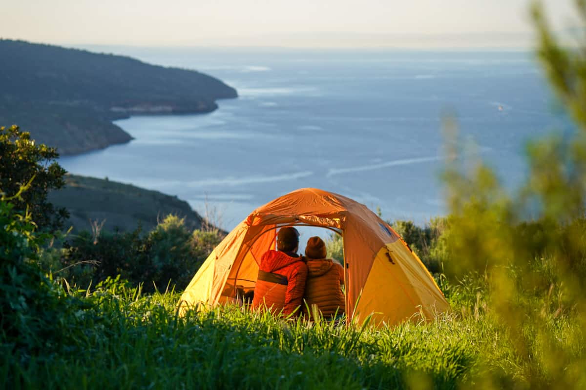 Couple sitting in a tent in the Del Norte Campground, overlooking the coastline of Santa Cruz island in Channel Islands National Park, California