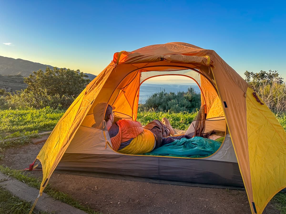 Man laying in a tent looking at the Pacific Ocean in the Del Norte Campground on Santa Cruz Island in the Channel Islands National Park, California