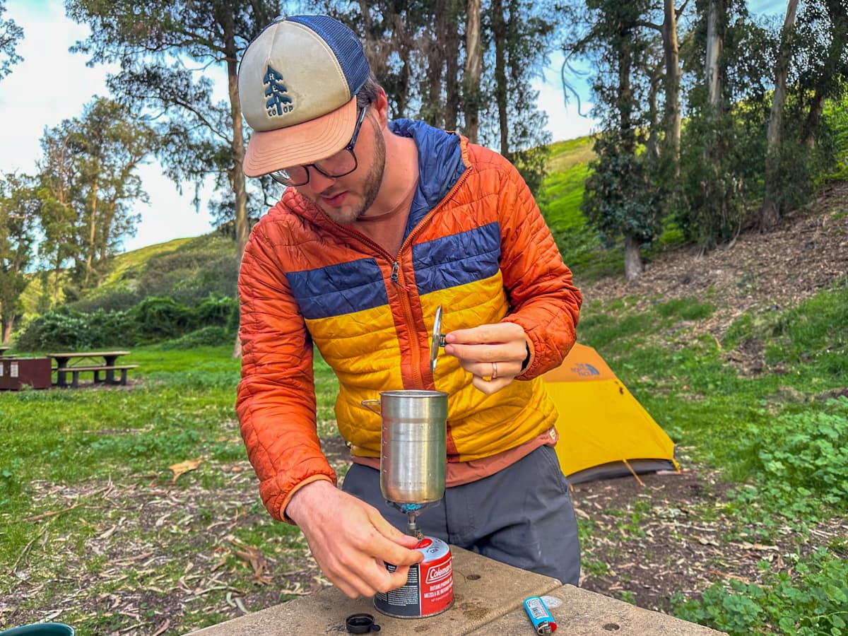 Man boiling water with a campstove on top of a picnic table in the Scorpion Campground on Santa Cruz Island in Channel Islands National Park, California