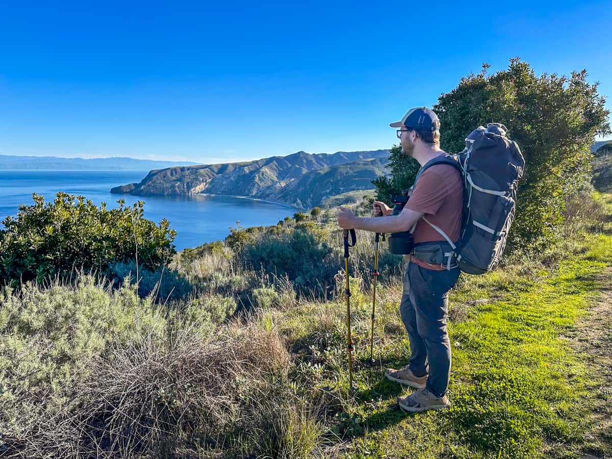 Man with a backpack with a sea cliff in the background in Santa Cruz island in the Channel Islands National Park, California
