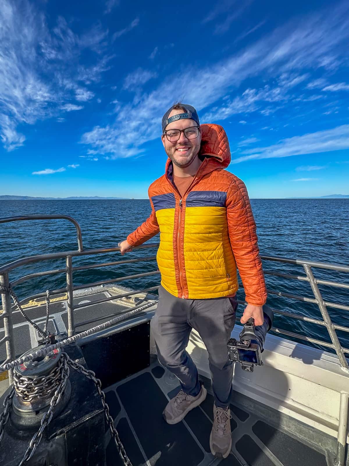 Smiling man holding a camera with a telephoto lens on the Island Packers ferry to Santa Cruz island in the Channel Islands National Park, California
