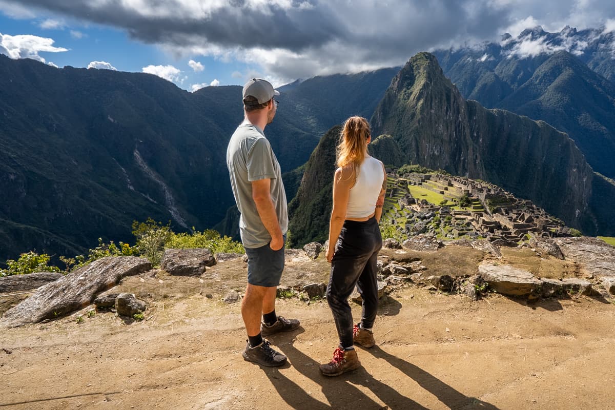Couple standing at a viewpoint overlooking the Machu Picchu ruins with Huayna Picchu in the background in Peru