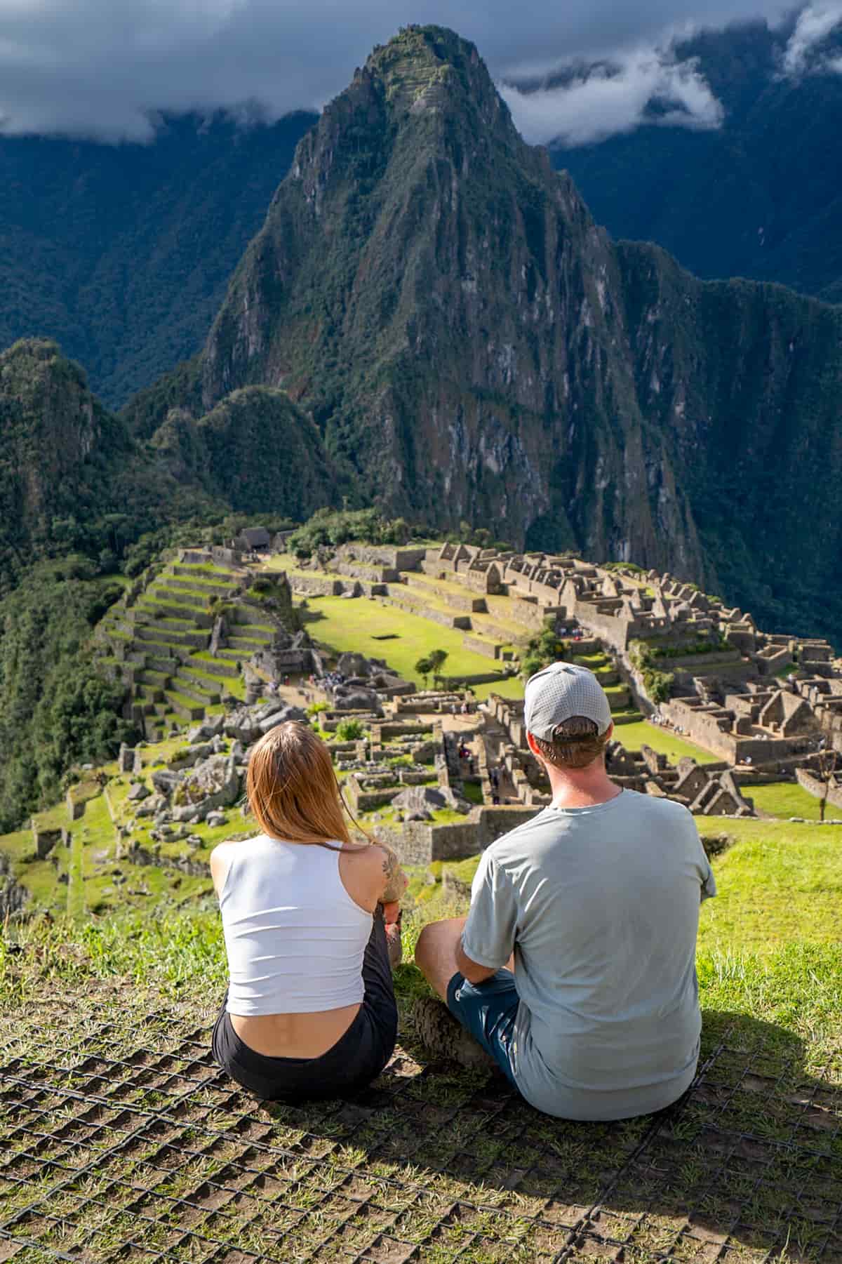 Couple sitting at an overlook with Machu Picchu and Huayna Picchu Mountain in the background in Peru