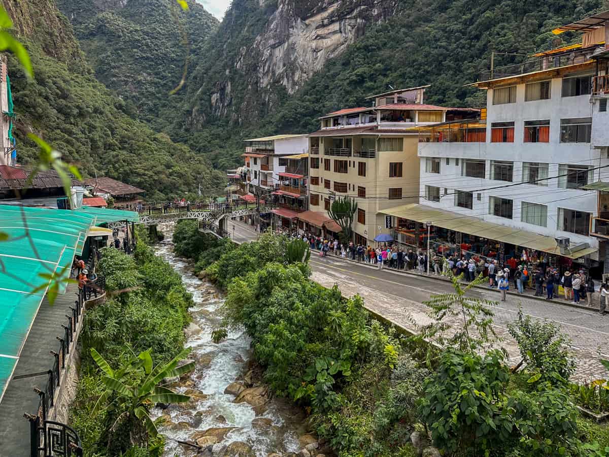 Tourists waiting in line for the bus on a street alongside the Urubamba River in Aguas Calientes, Peru