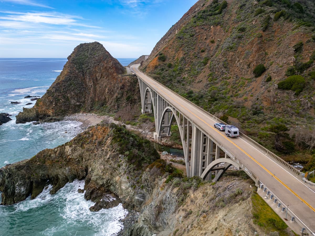 SUV pulling a Safari Condo Alto A1752 along a bridge on the Pacific Coast Highway along the coastline in Big Sur, California