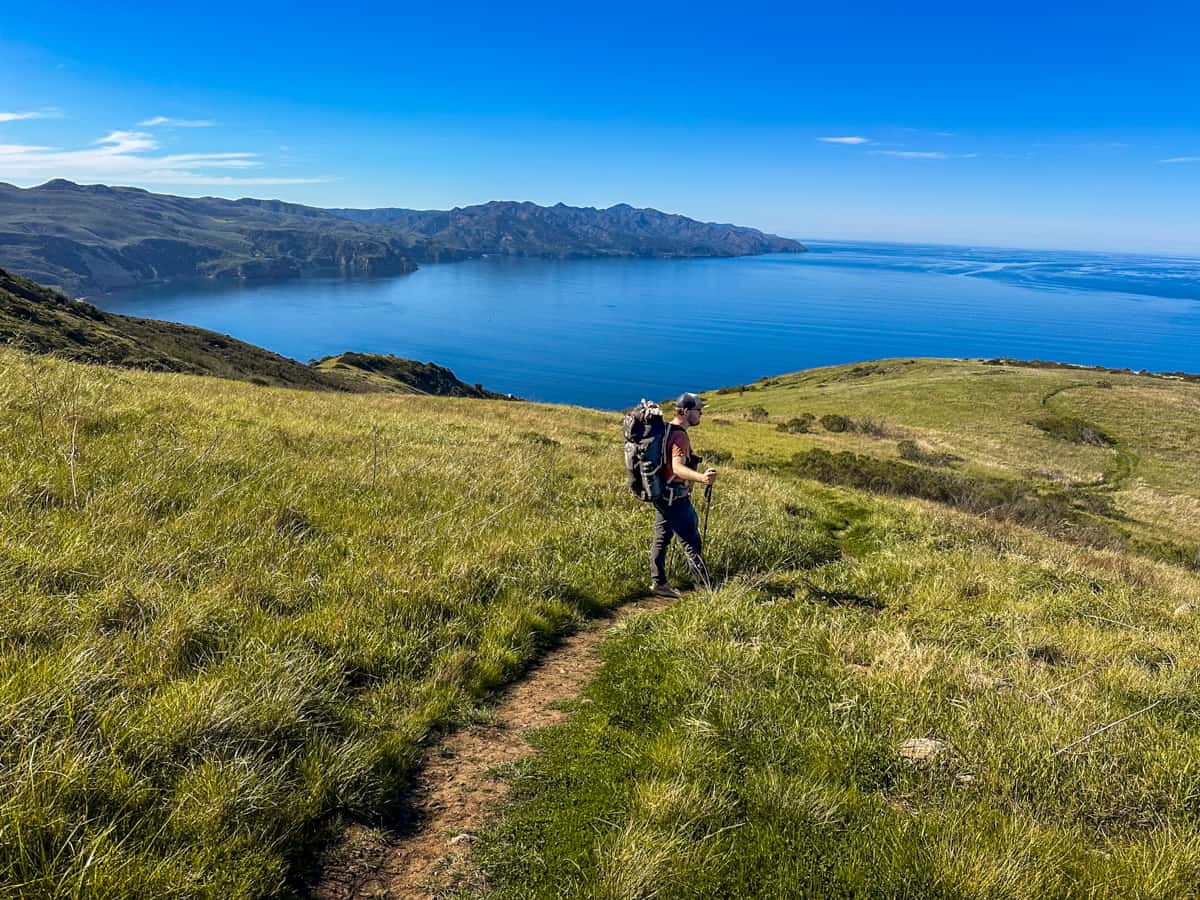 Man hiking down a grassy hill along the Montanon Ridge Loop Trail on Santa Cruz island in Channel Islands National Park in California