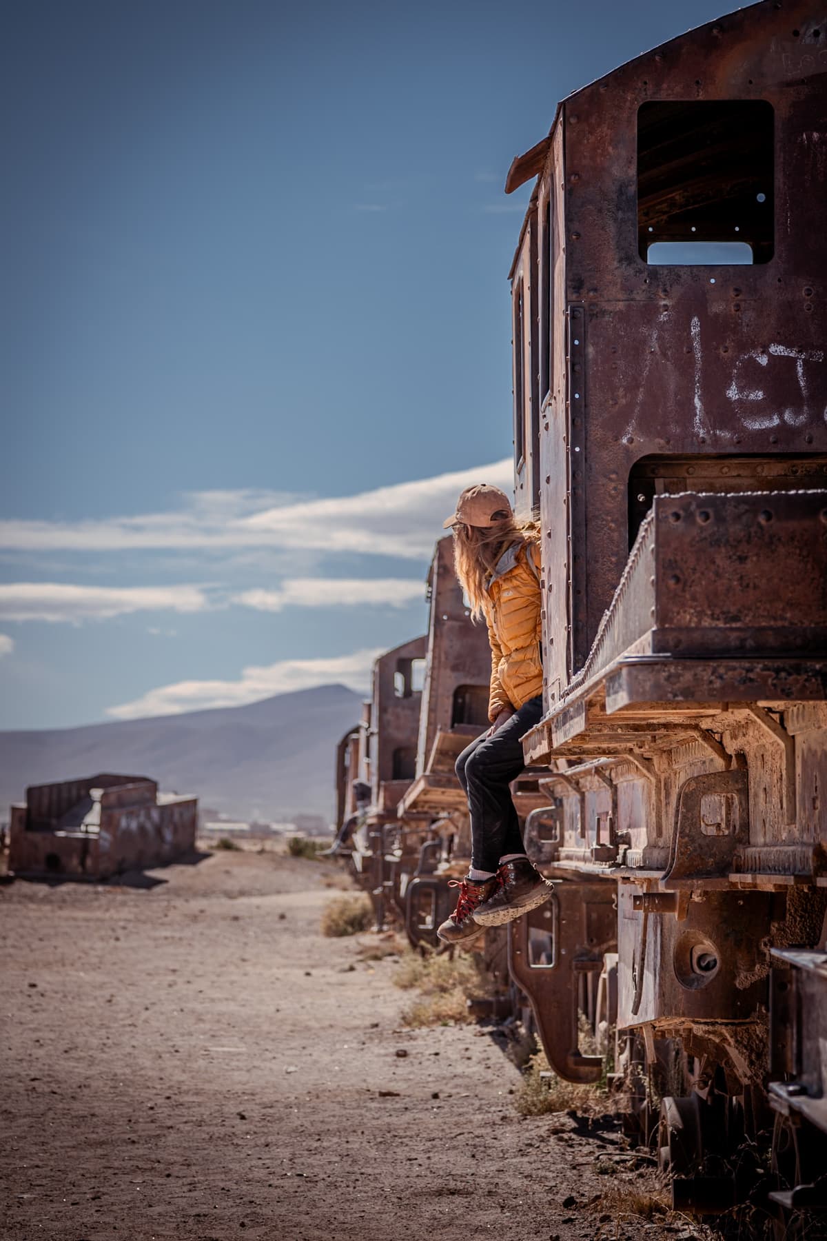 Woman sitting on a rusted train car in the train cemetry near the Uyuni Salt Flats in Bolivia