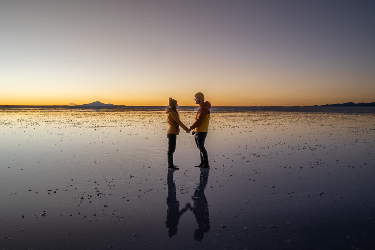 Couple holding hands while standing on the flooded Uyuni Salt Flats in Uyuni, Bolivia