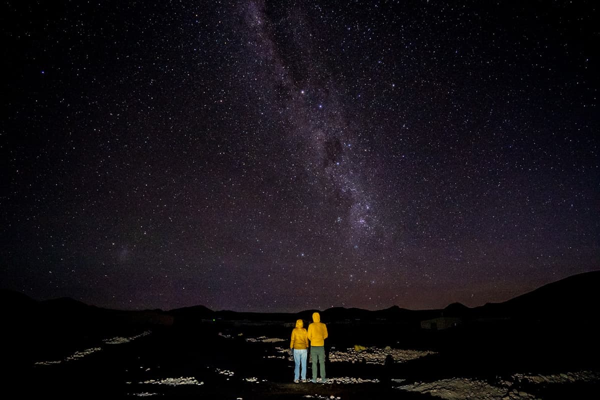 Couple holding hands under the Milky Way and other stars in the Uyuni Salt Flats of Bolivia at night
