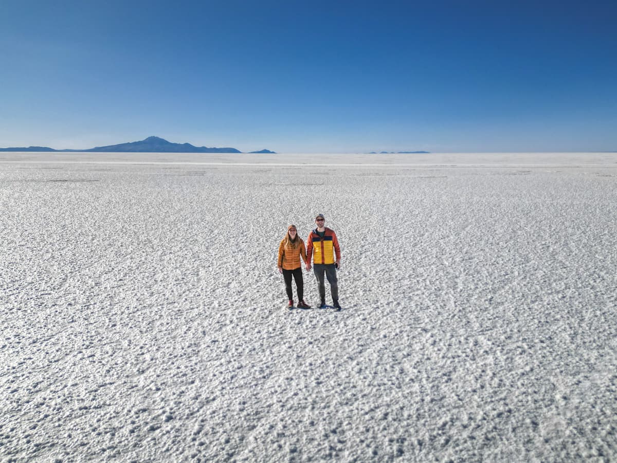 Couple holding hands on the Uyuni Salt Flats with mountains in the background in Uyuni, Bolivia