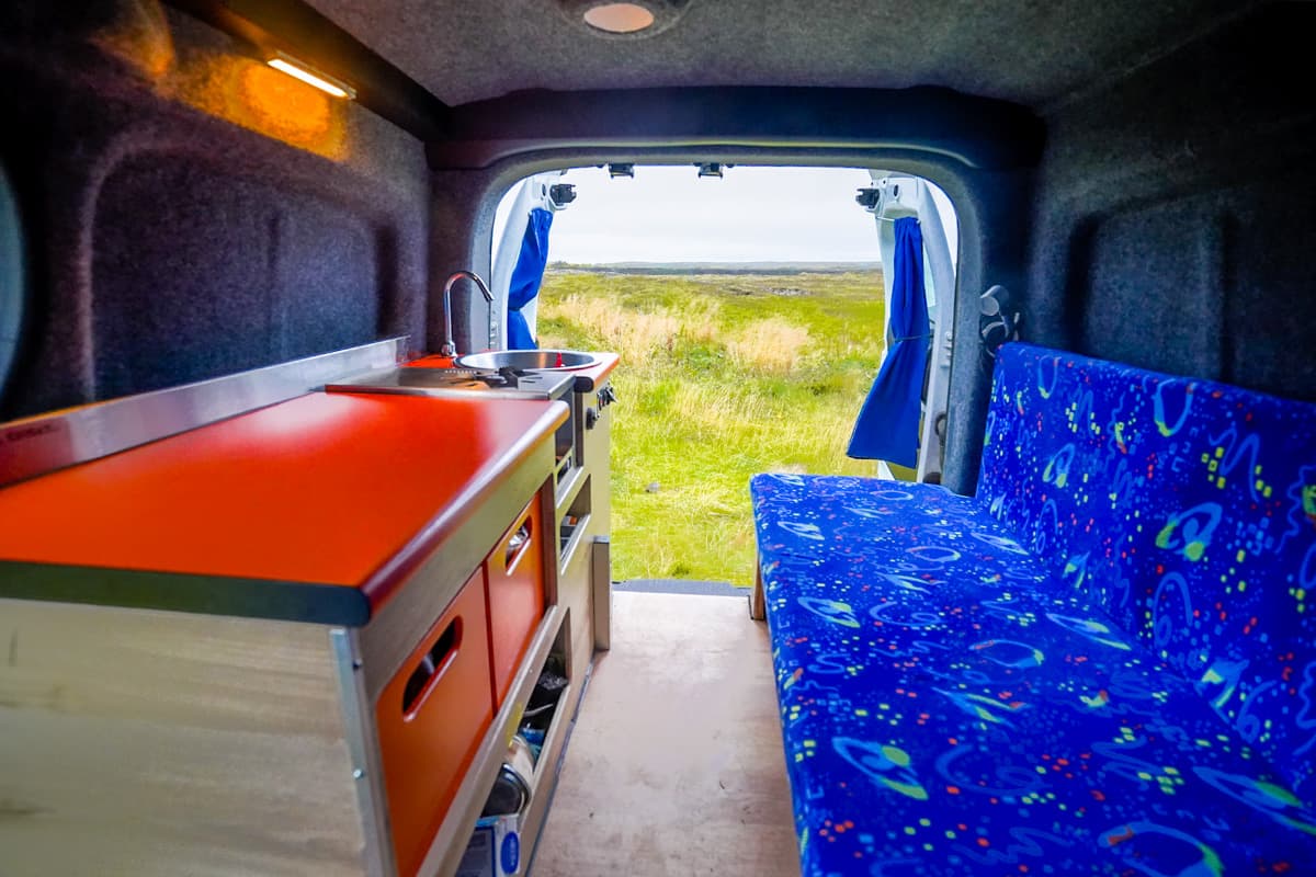 Interior shot of couch and kitchen setup in the Happy 1 model of the Happy Camper rentals in Iceland