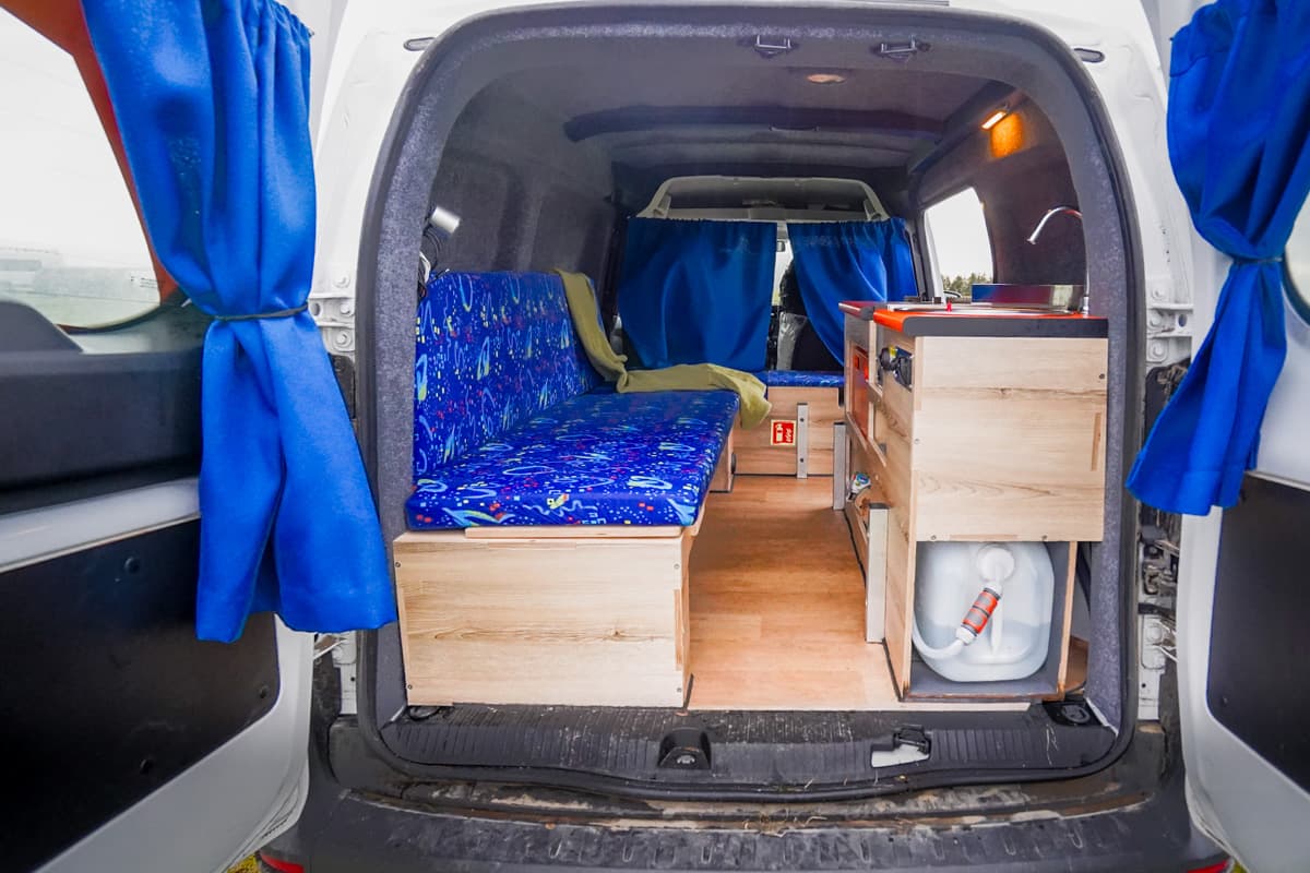 Interior shot of a couch and kitchen setup in the Happy 1 campervan model of Happy Campers campervans in Iceland