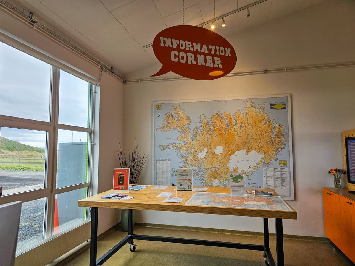 Sign for an "information corner" and large map of Iceland on a wall in the Happy Campers campervan rental office in Iceland