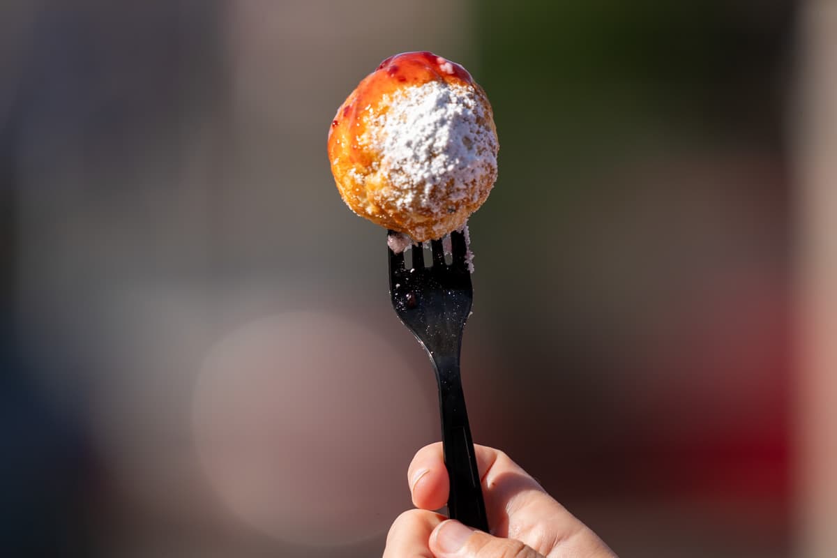 Fork holding aebleskivers, covered with powdered sugar and raspberry jam, at Solvang Restaurant in Solvang, California