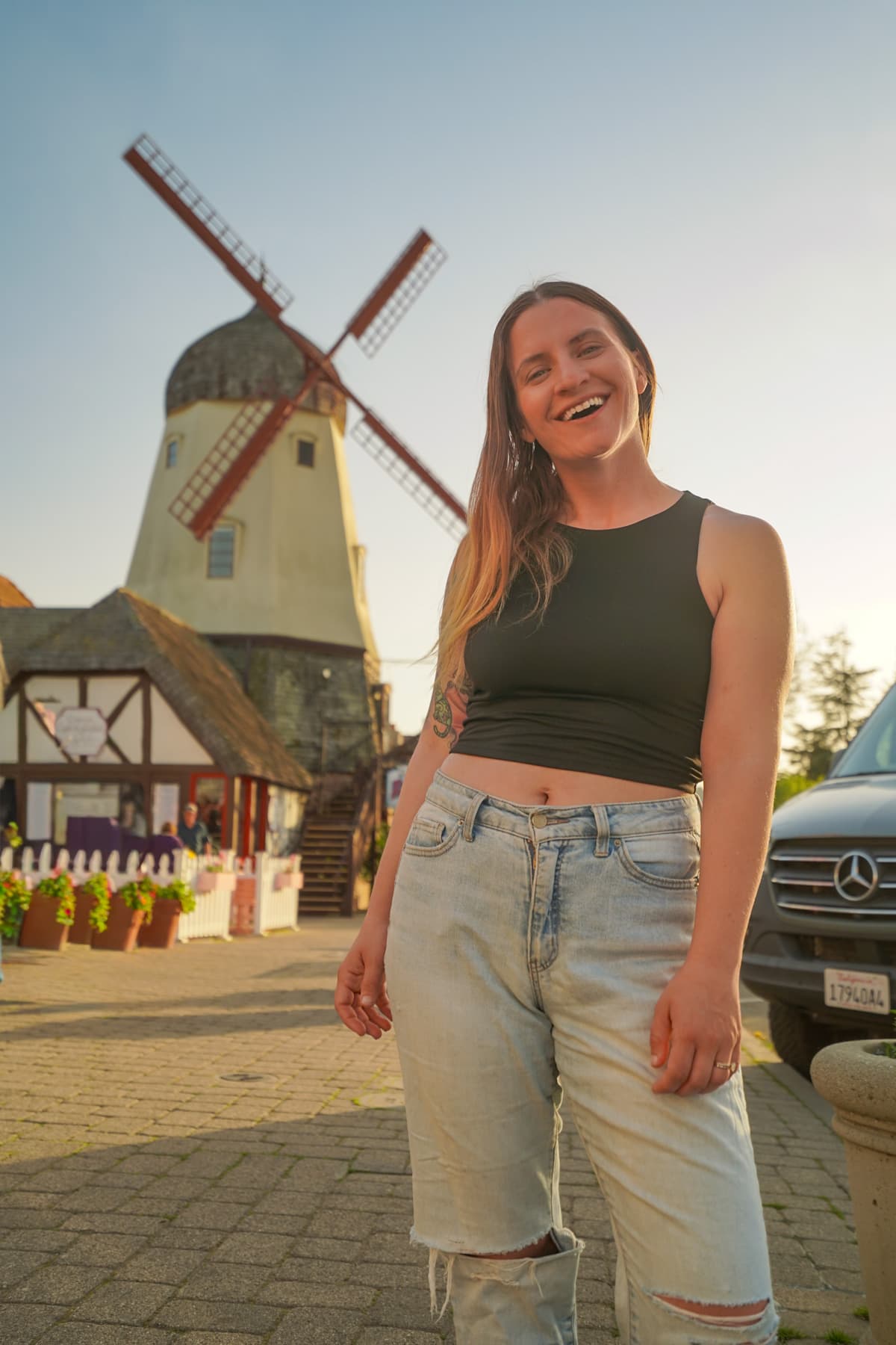 Smiling woman standing in front of a windmill on Copenhagen Drive of Solvang, California