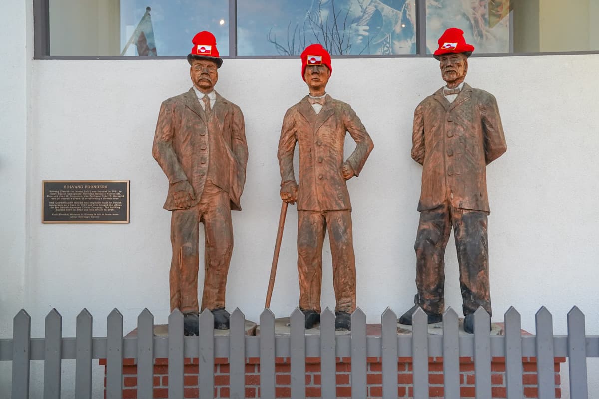 Bronze statues of the founders of Solvang wearing beanies with Greenland's flag to signify Solvang's support of Greenland's autonomy in downtown Solvang, California