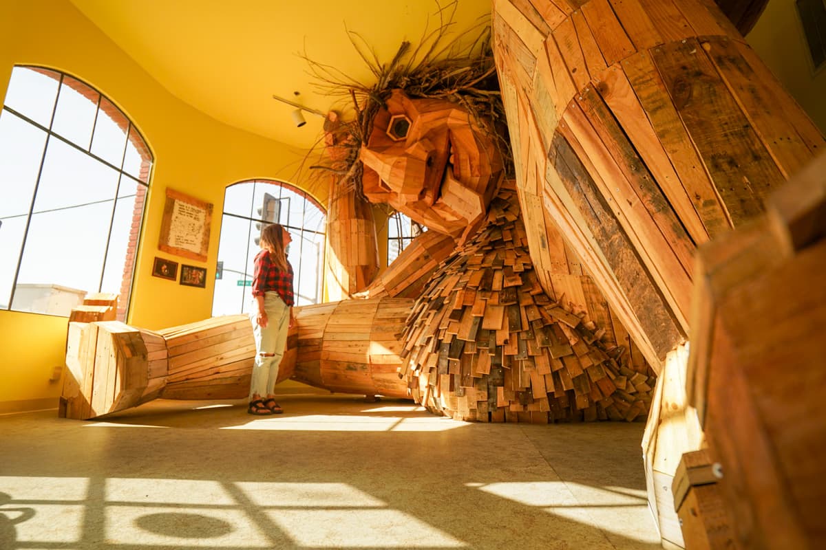 Woman looking at a wooden troll sculpture at the California Nature Art Museum in Solvang, California