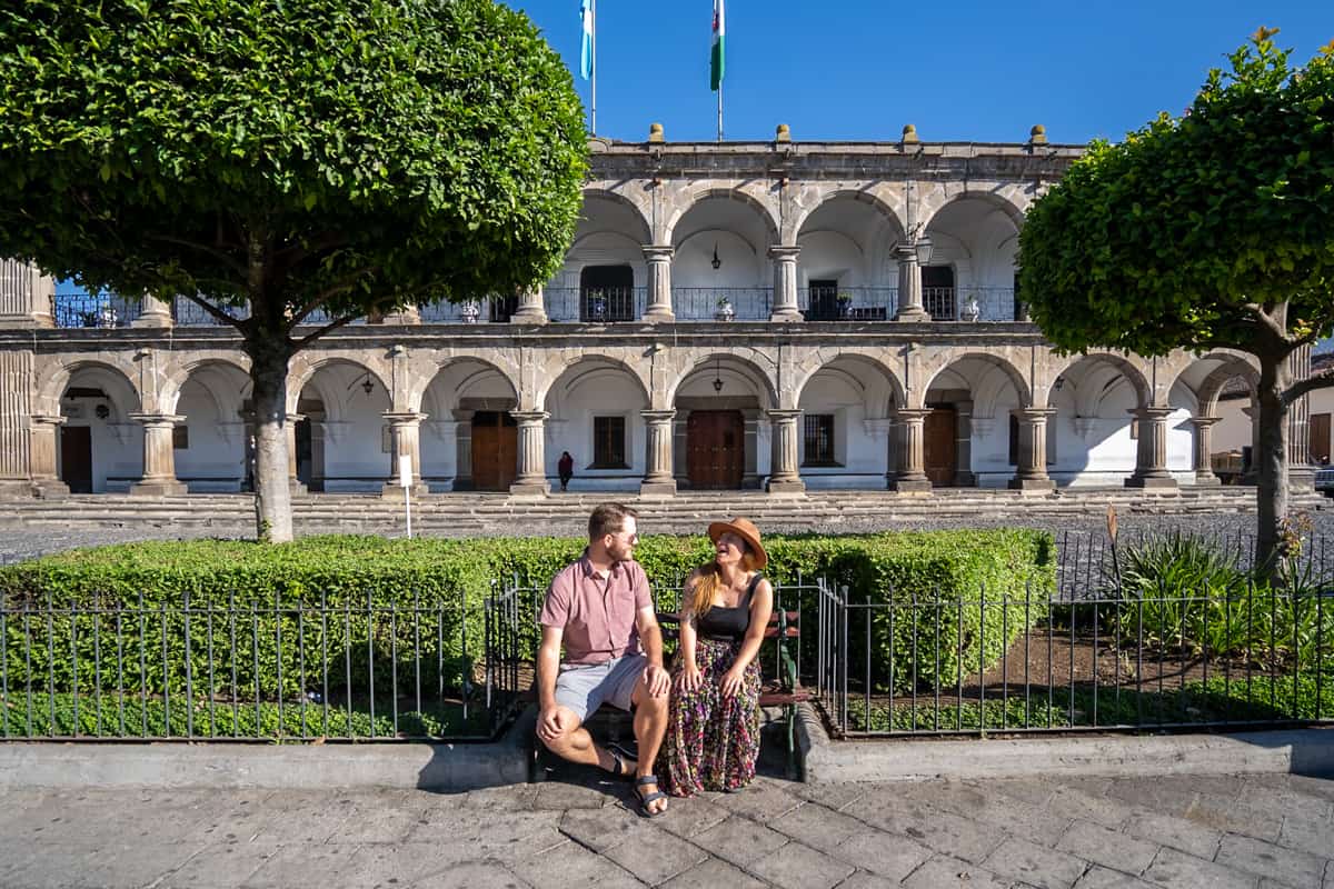 Couple sitting on a bench in front of a colonial building in Antigua, Guatemala