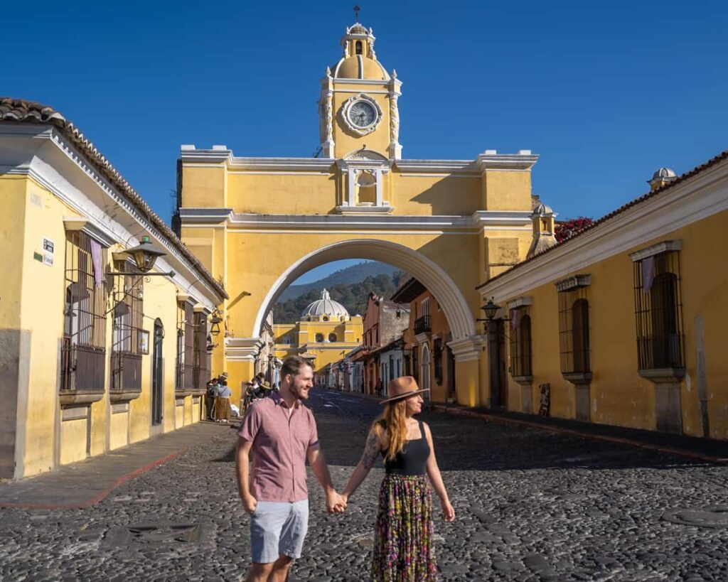 Couple standing in front of Arco de Santa Catalina in Antigua, Guatemala