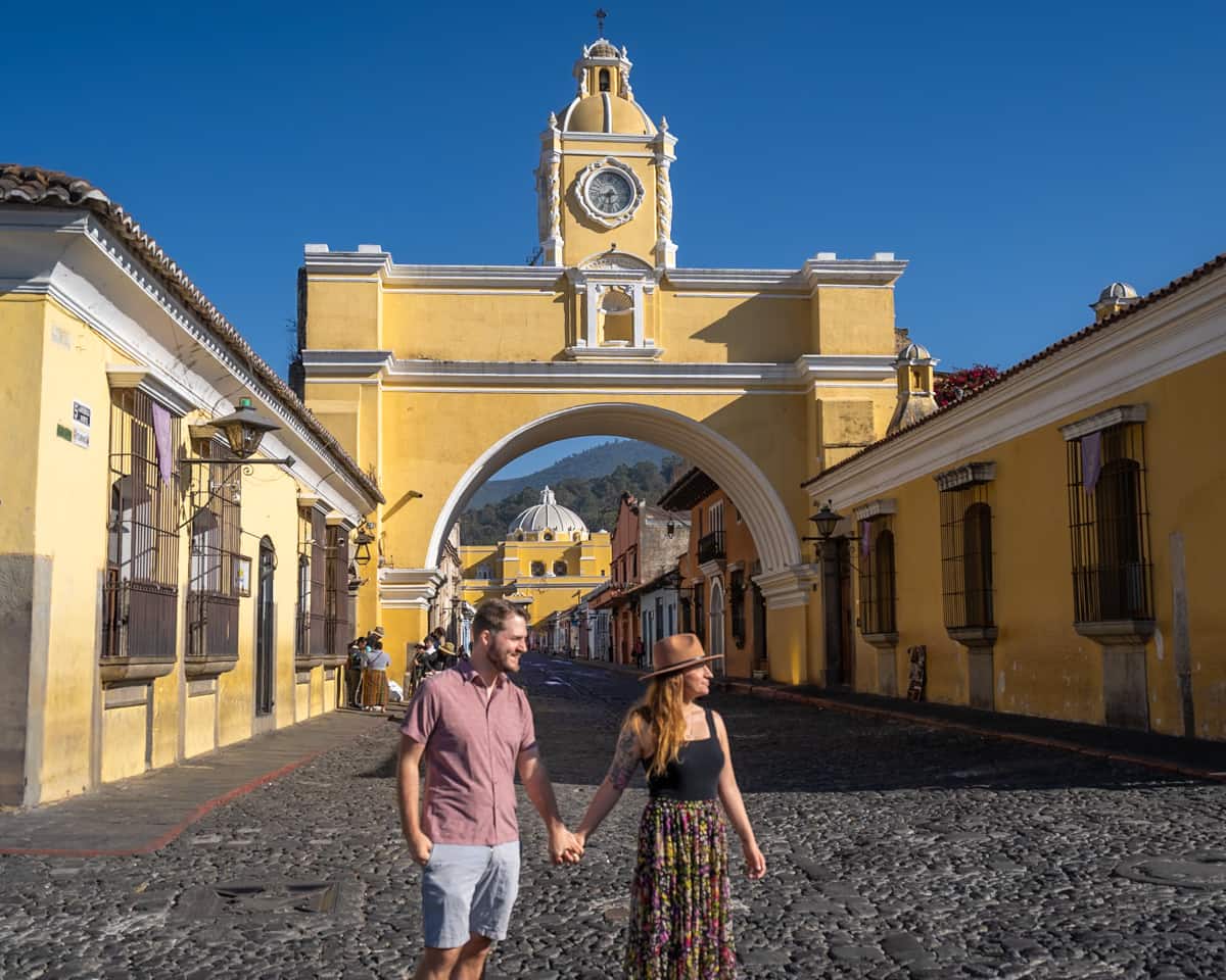 Couple standing in front of Arco de Santa Catalina in Antigua, Guatemala