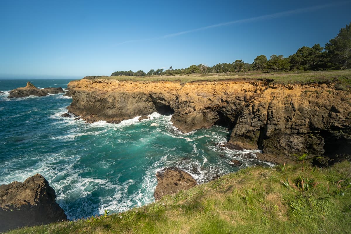 Rugged cliffsides along a grassy headlands and the Pacific Ocean along the Mendocino Headland Trail in Mendocino, California 