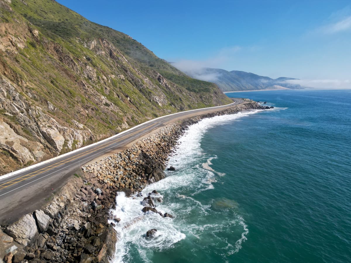 Aerial view of Highway One curving around green mountains in California