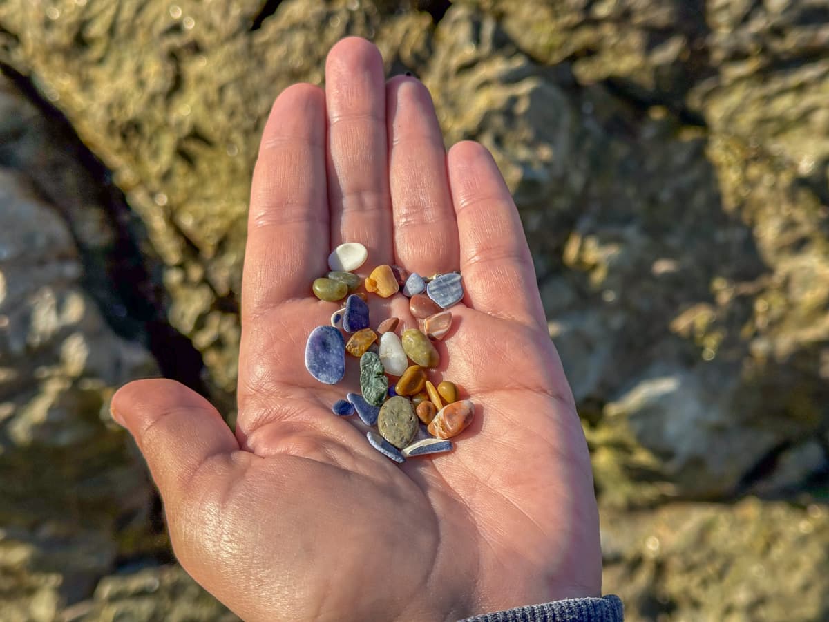Woman's hand holding colorful pebbles at Glass Beach in Fort Bragg, California