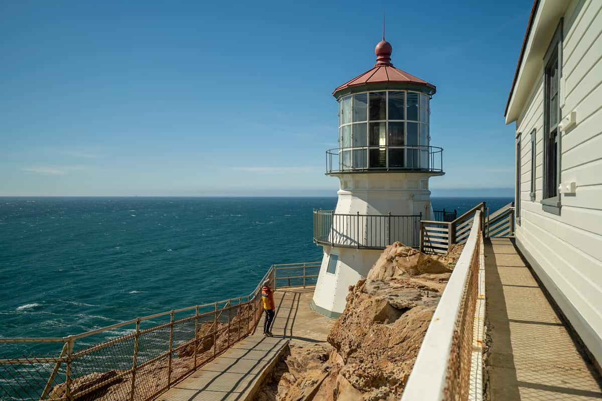Man looking at the Point Reyes Lighthouse with the Pacific Ocean in the background in Point Reyes National Seashore in California