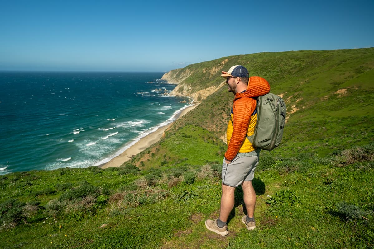 Man standing along the Tomales Point Trail with Driftwood Beach in the background in Point Reyes National Seashore in California